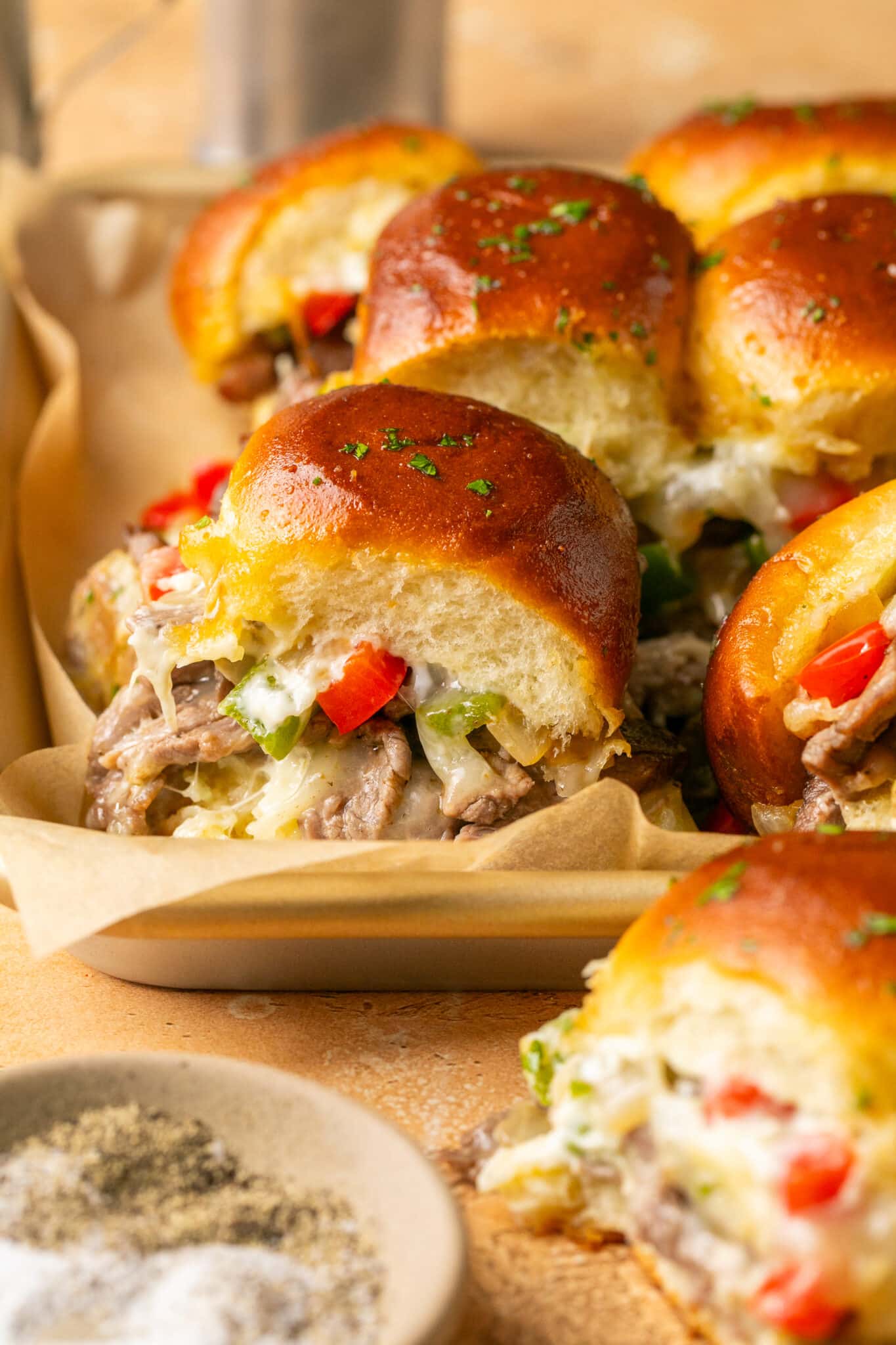 philly cheesesteak sliders on a baking cheese lined with parchment paper. 