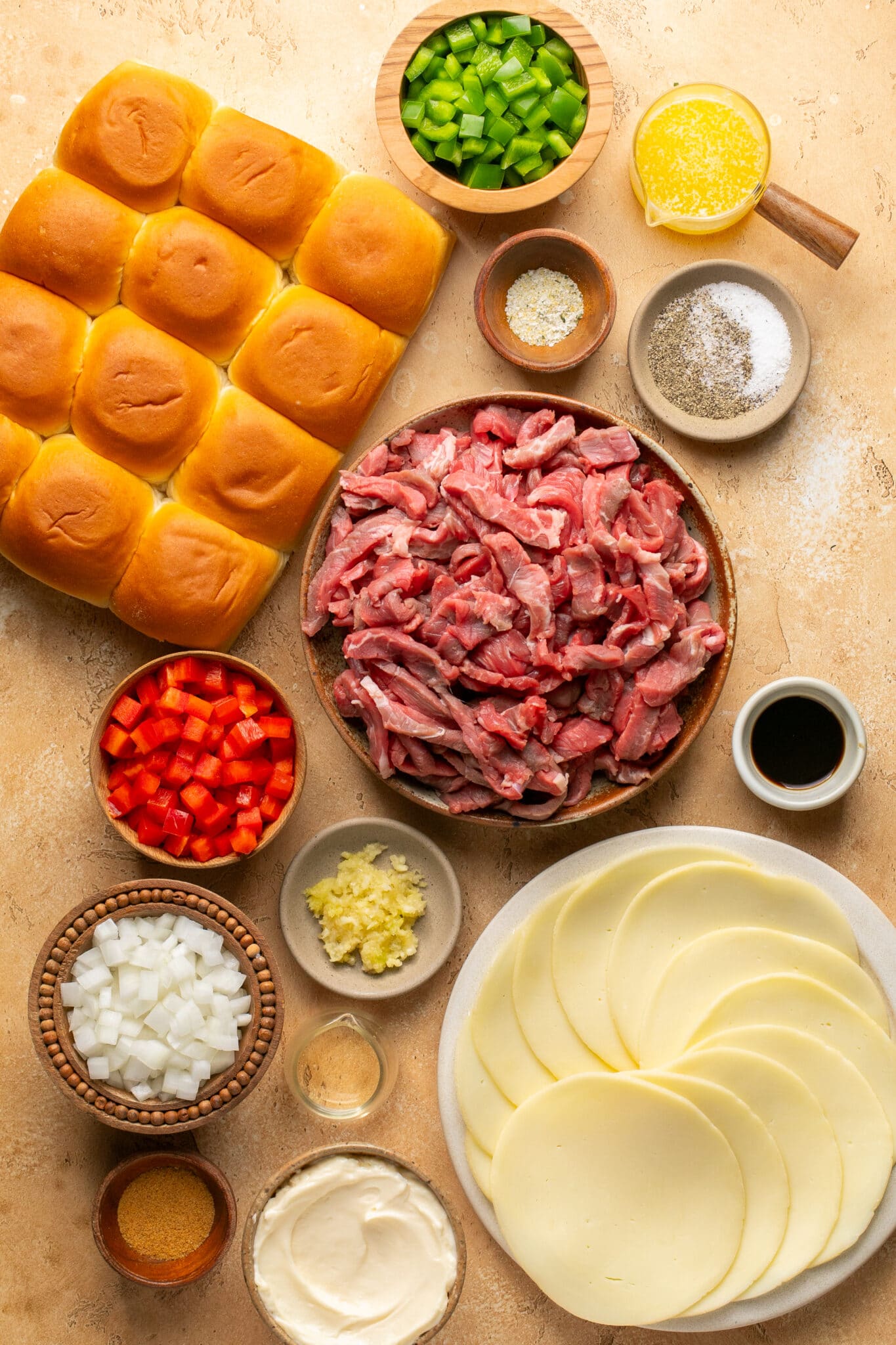 ingredients in small bowls needed to make philly cheesesteak sliders. 