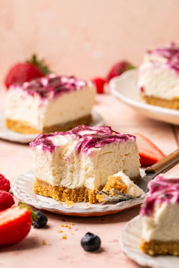 a slice of cheesecake with a fork taking a bite out of it. 