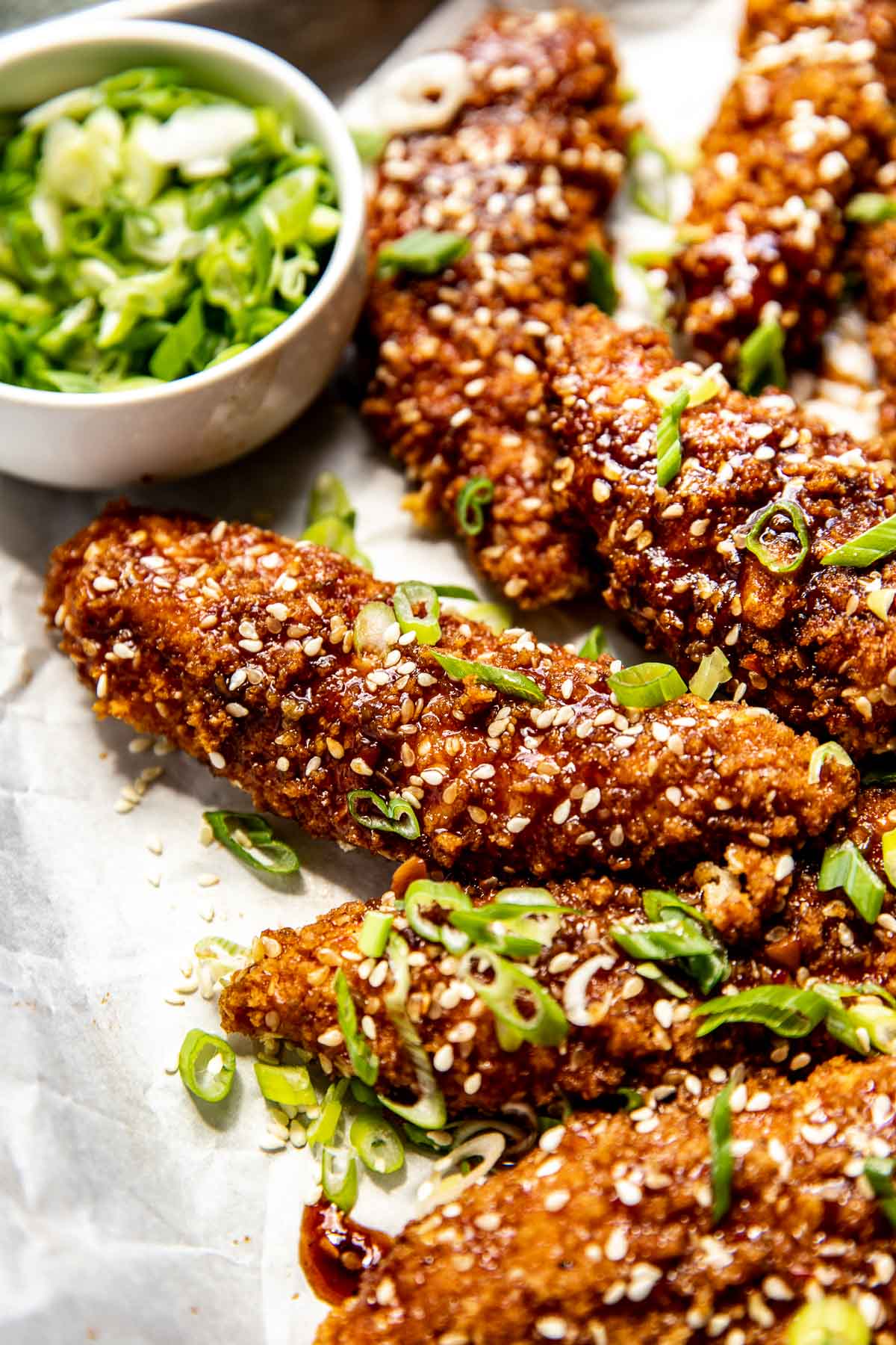 sesame chicken tenders garnished with green onions. 