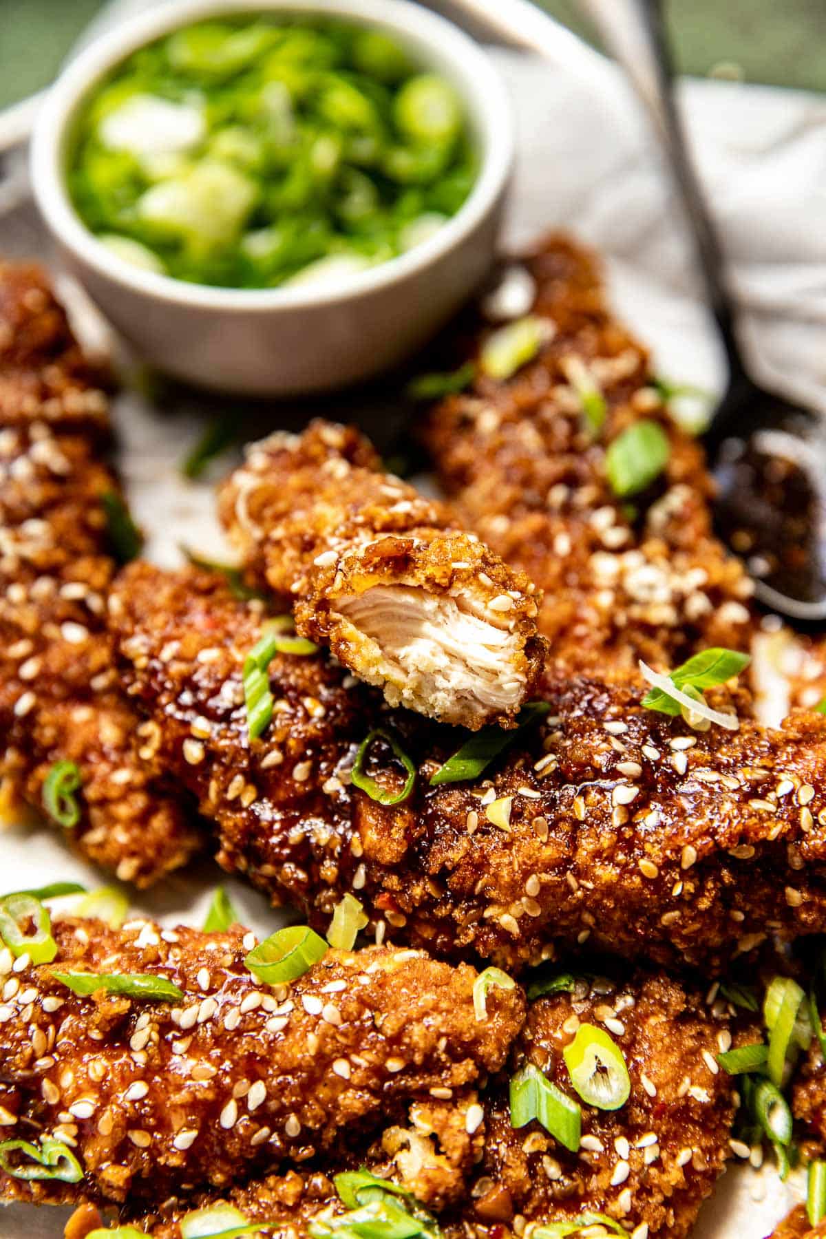 sesame chicken tenders garnished with green onions. 