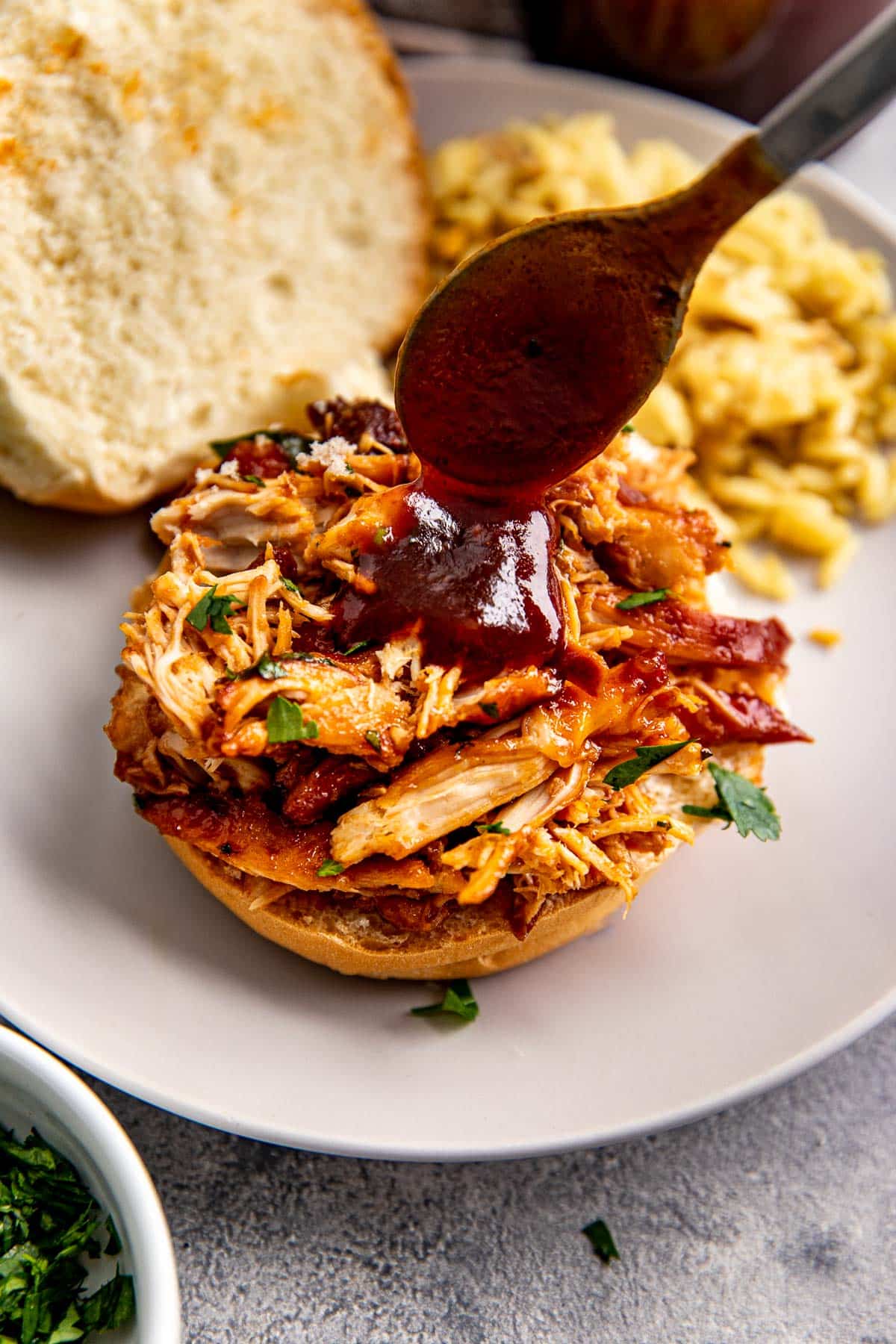 shredded bbq chicken on a bun with bbq sauce on top. 