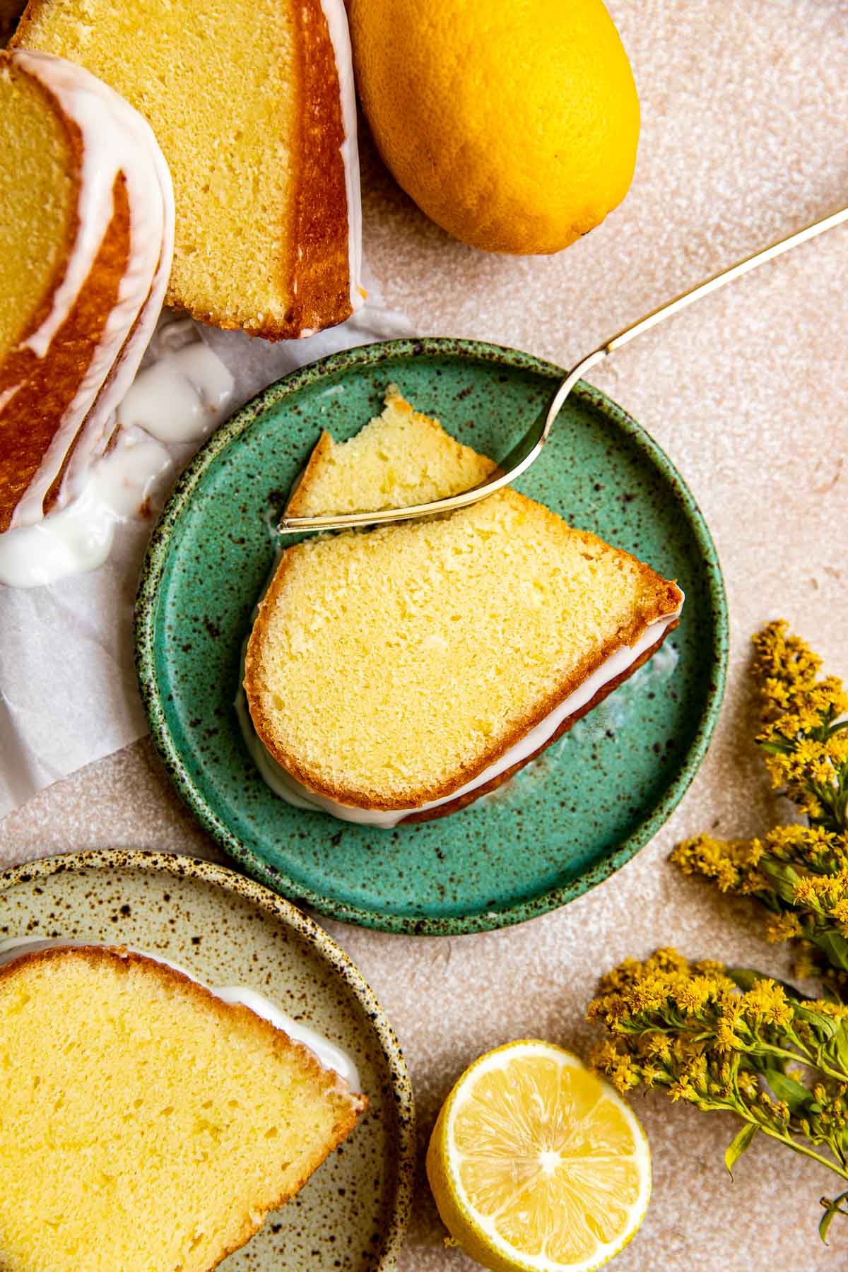 a fork taking a bite out of lemon pound cake on a green speckled plate.