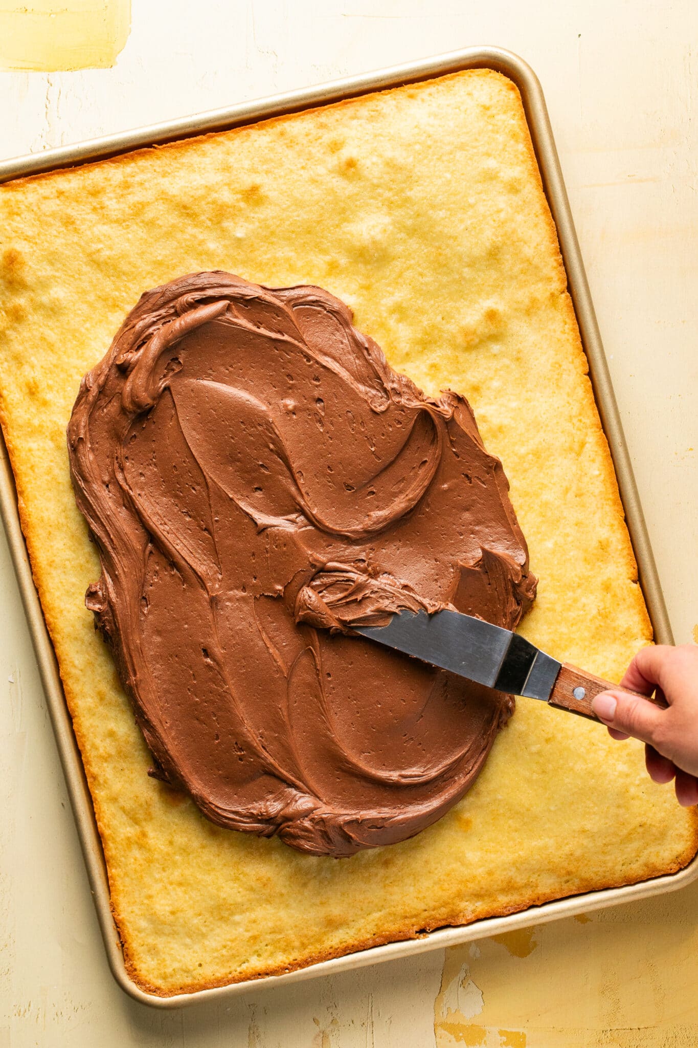 yellow cake in a sheet pan with chocolate frosting on top. 