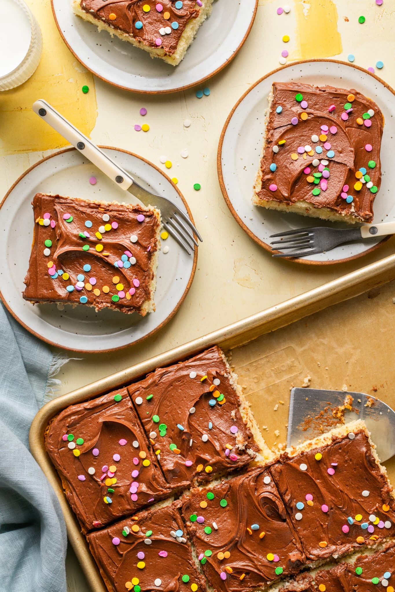 a yellow sheet cake with chocolate frosting and colorful sprinkles on top. 