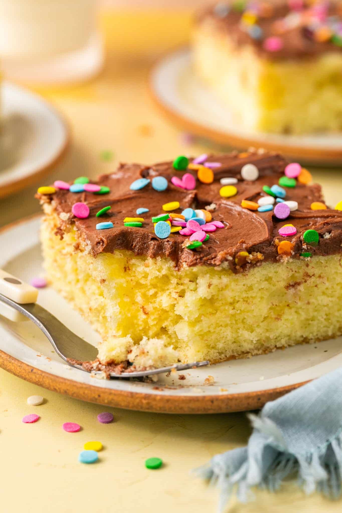 yellow cake with chocolate frosting and sprinkles on top. 