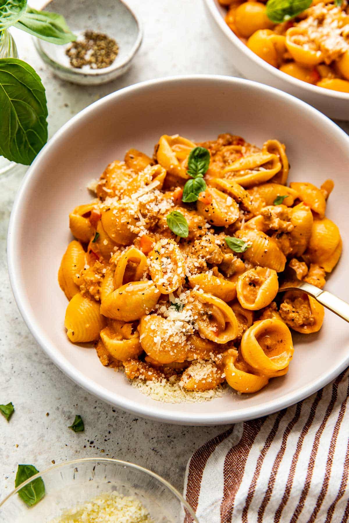 ground turkey pasta in a white bowl garnished with basil. 