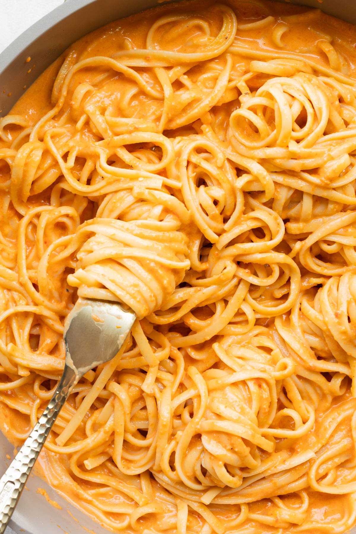 close up image of bell pepper pasta on a gold fork. 