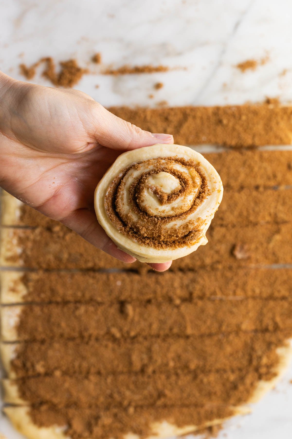 am image of a cinnamon roll rolled on in a womans hand. 