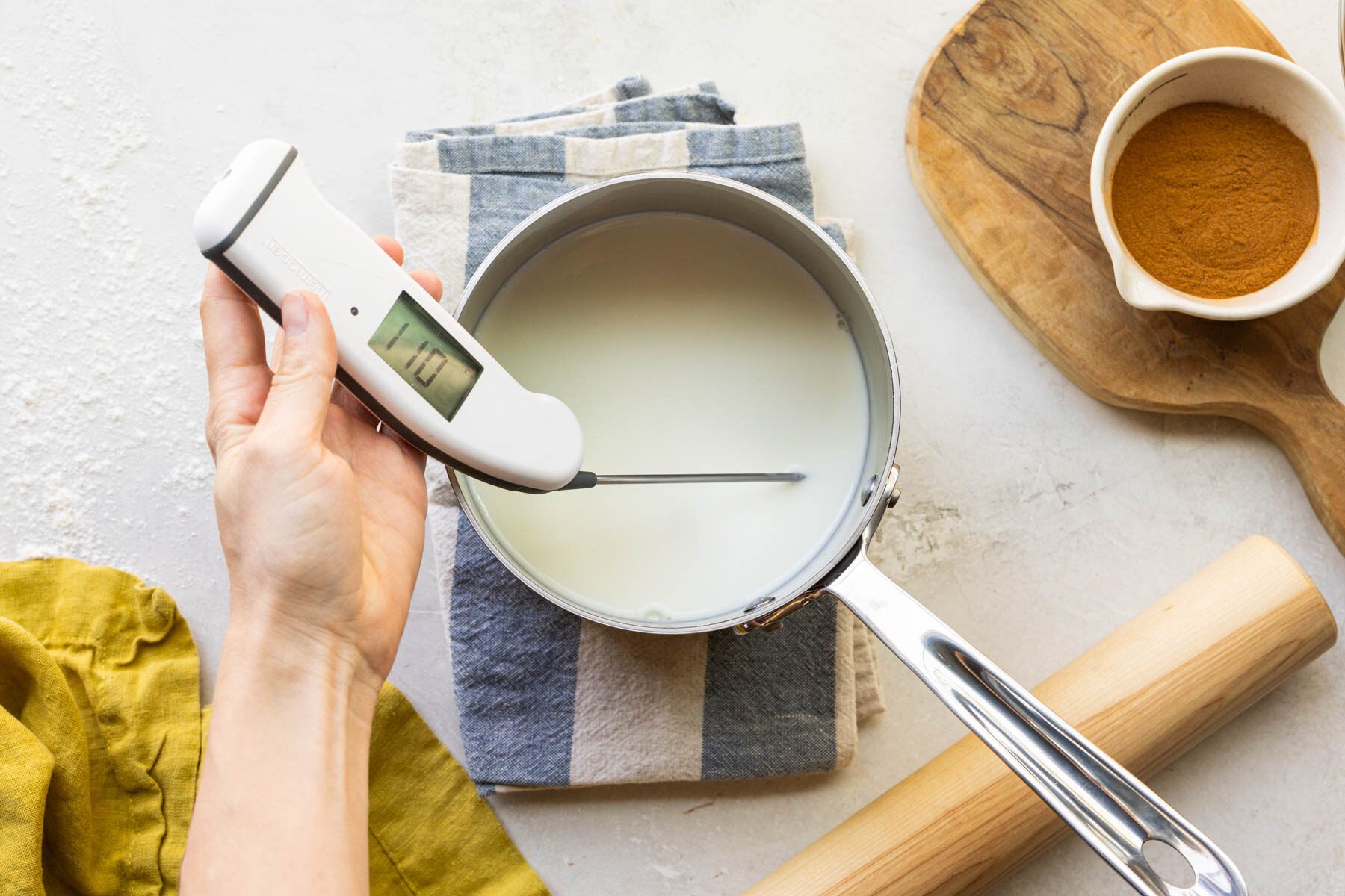 milk in a sauce pan with a thermometer taking the temperature of the milk. 