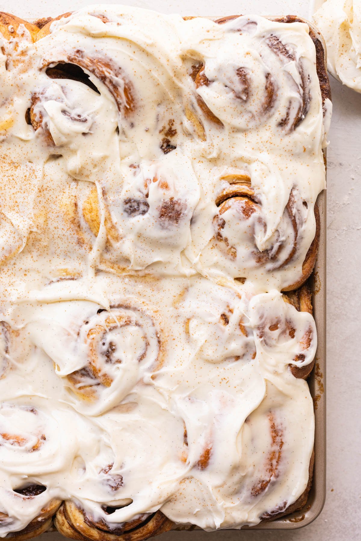 cinnamon rolls on a sheet pan with frosting on top. 