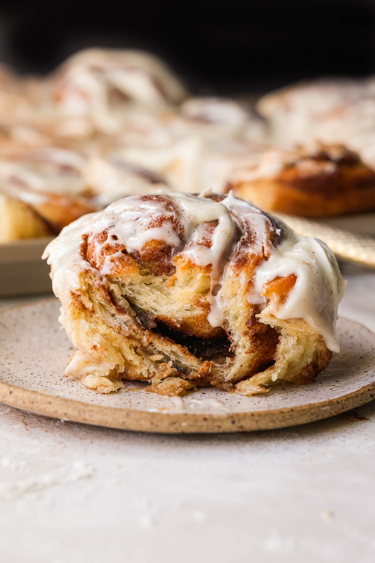 a cinnamon roll on a plate with cream cheese frosting on top. 