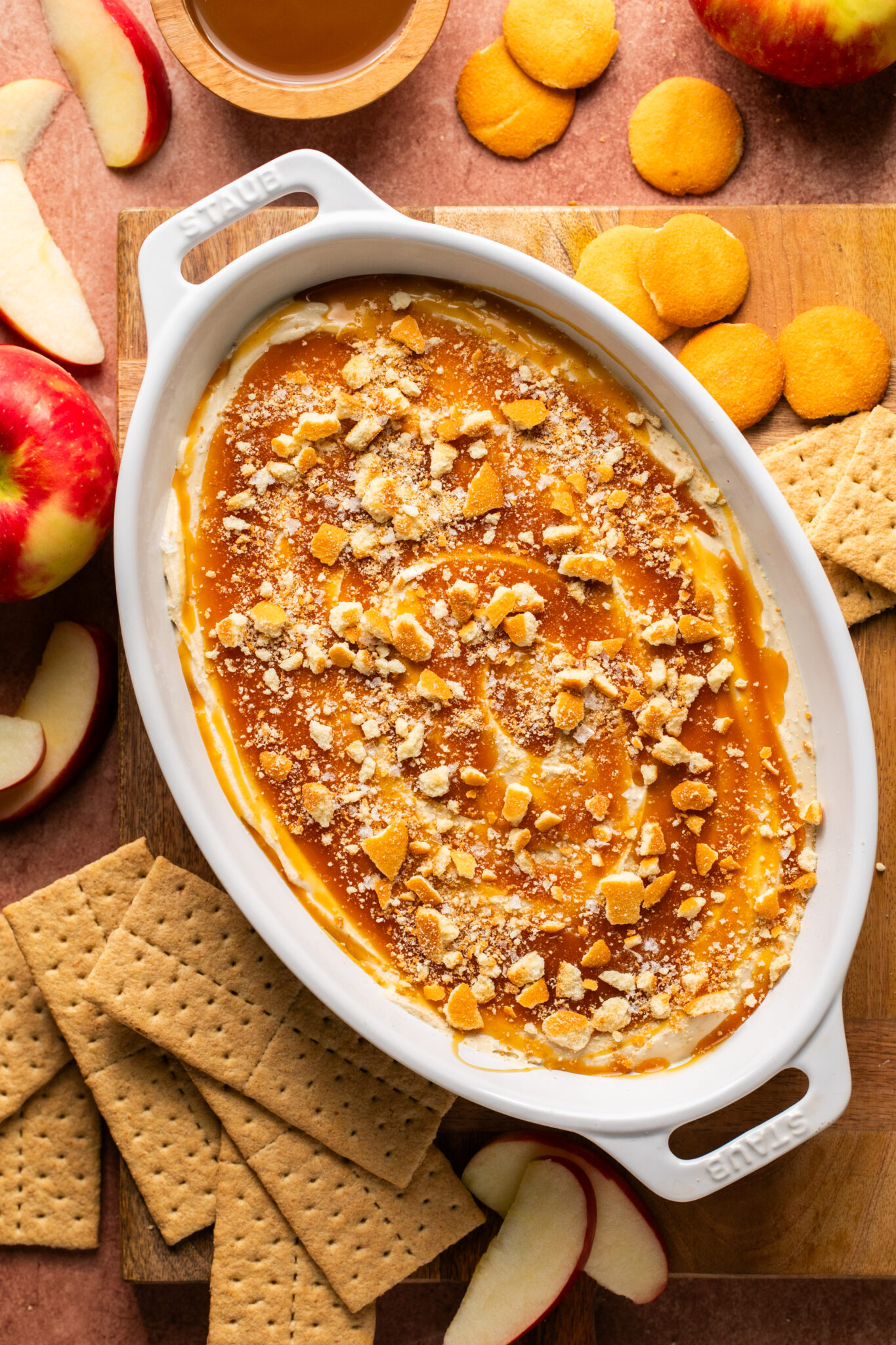 cheesecake dip in a ceramic dish covered with caramel and nilla wafers. 