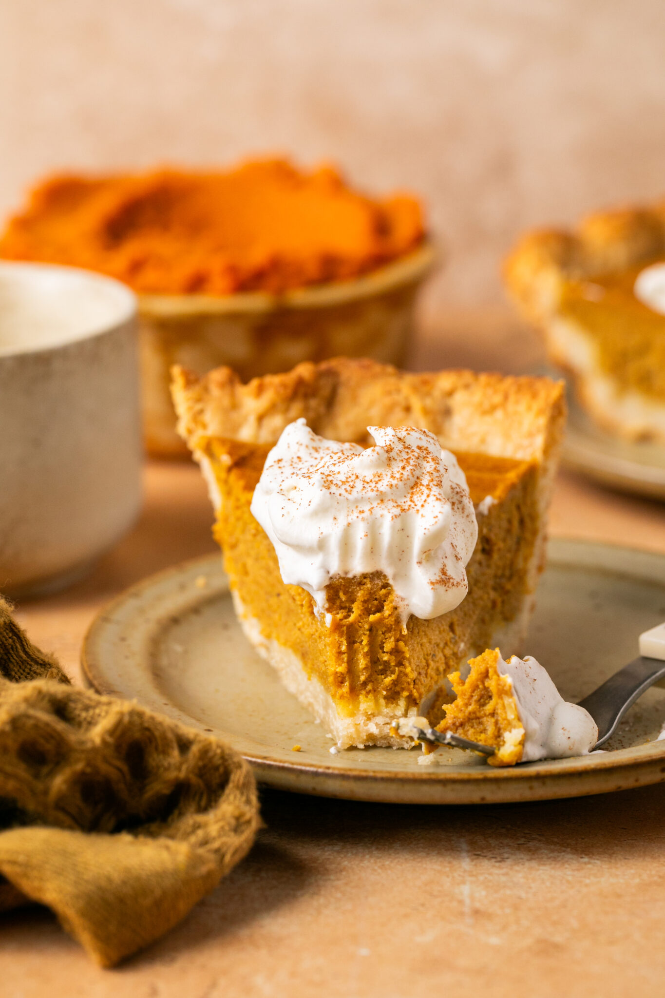 a bite being taken out of a pumpkin pie on a plate. 