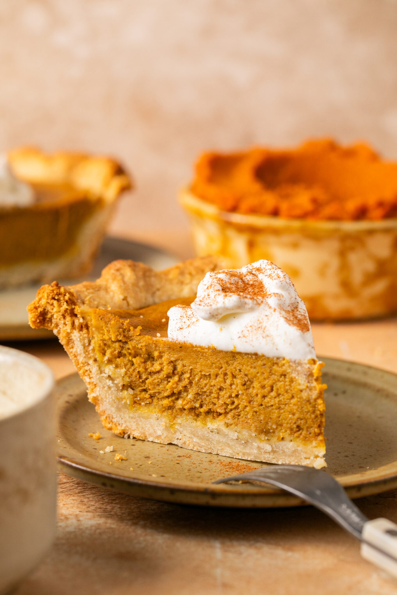 a slice of pumpkin pie on a brown plate. 