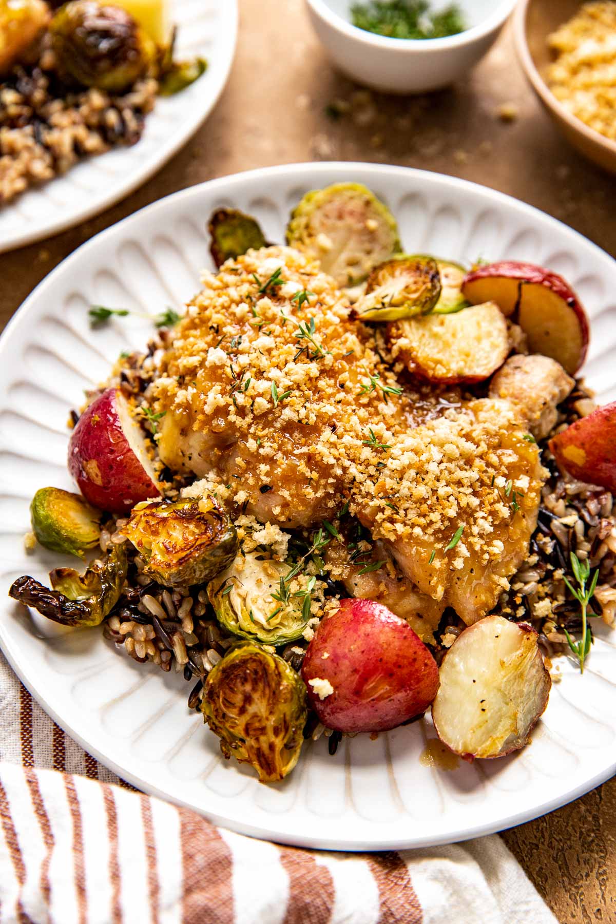 wild rice, brussels, red potatoes, and chicken thighs on a white plate. 