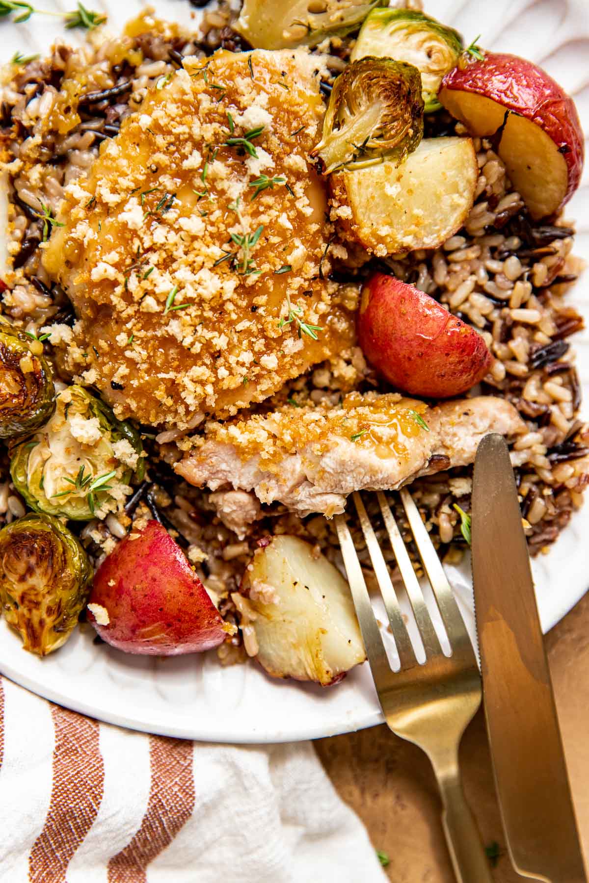 a close up image o a fork and knife cutting into maple dijon chicken. 