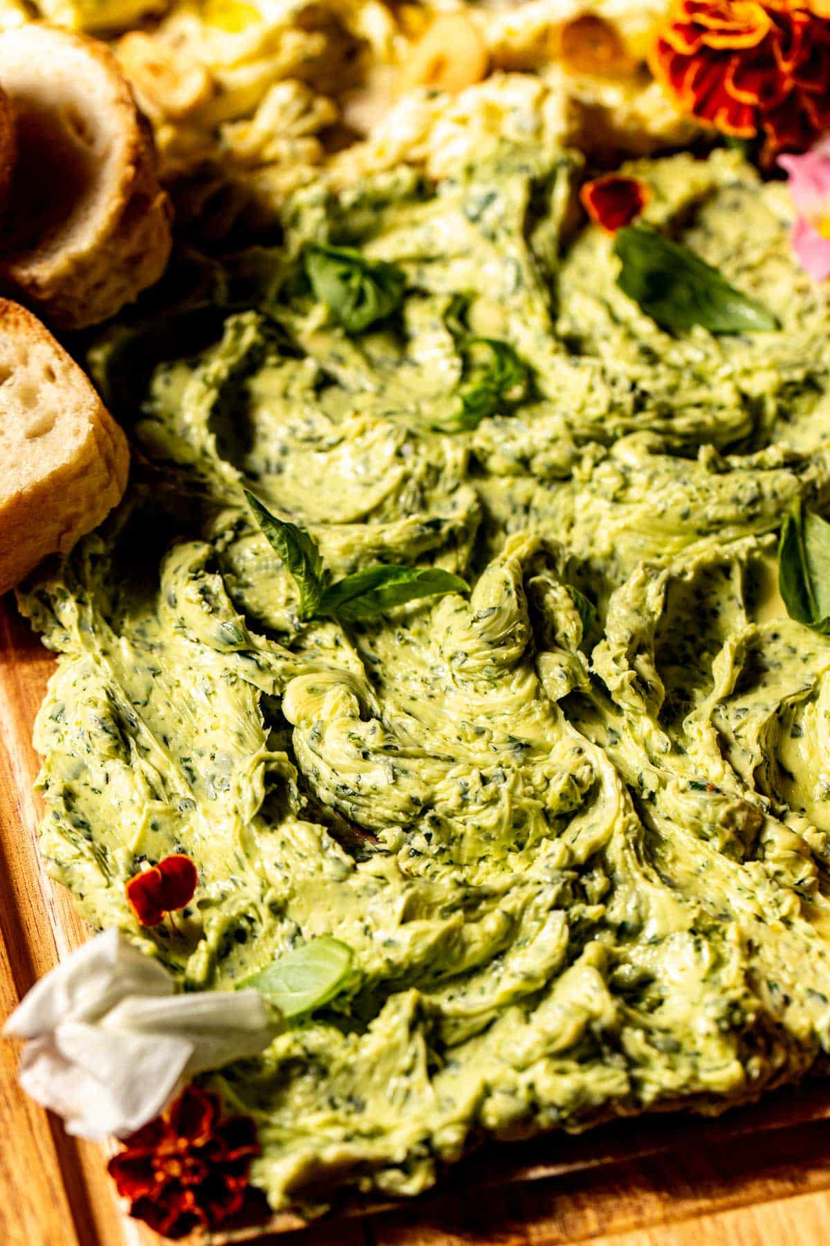 an up close image of basil butter spread on a wooden cutting board.