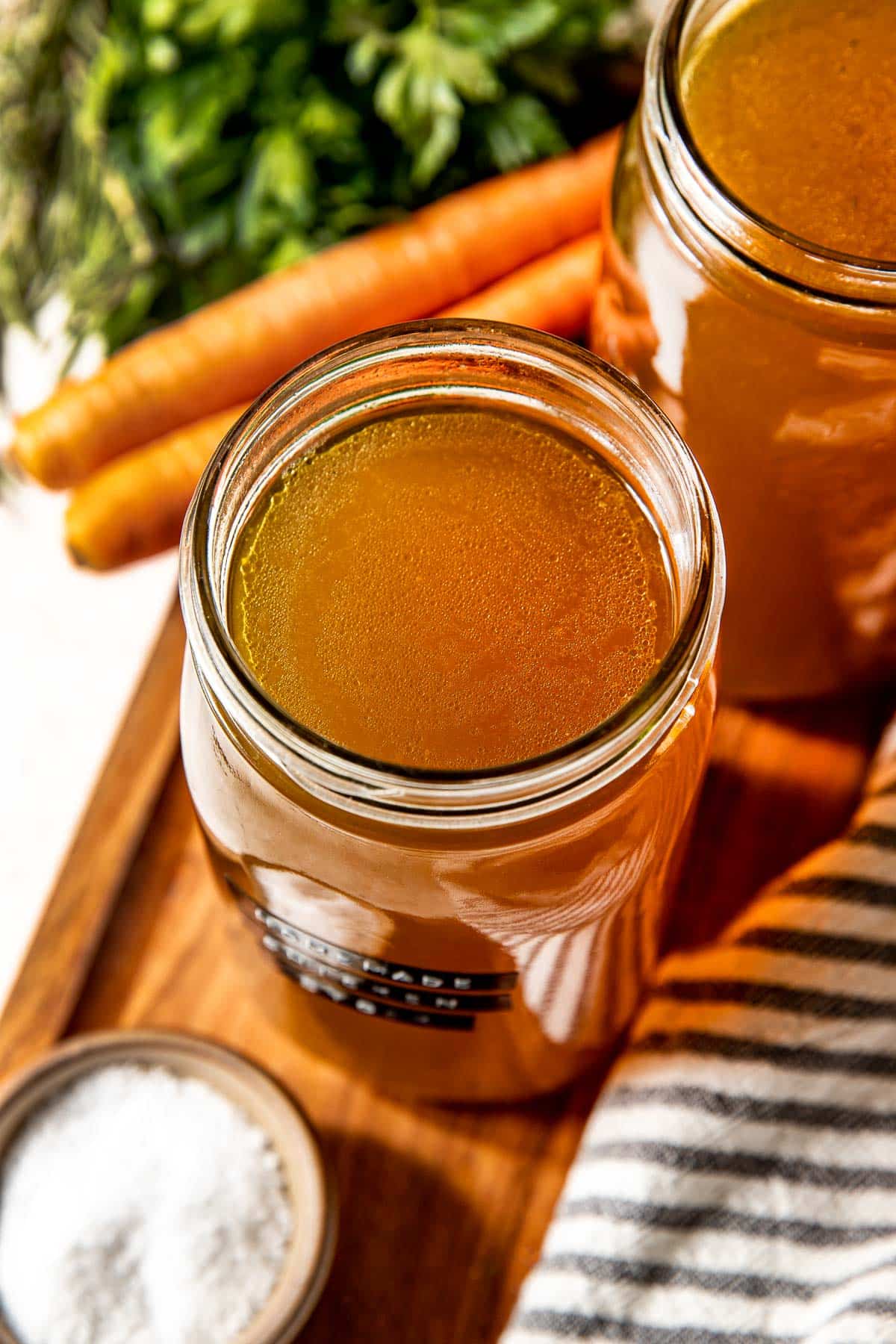 homemade chicken stock in mason jar on cutting board