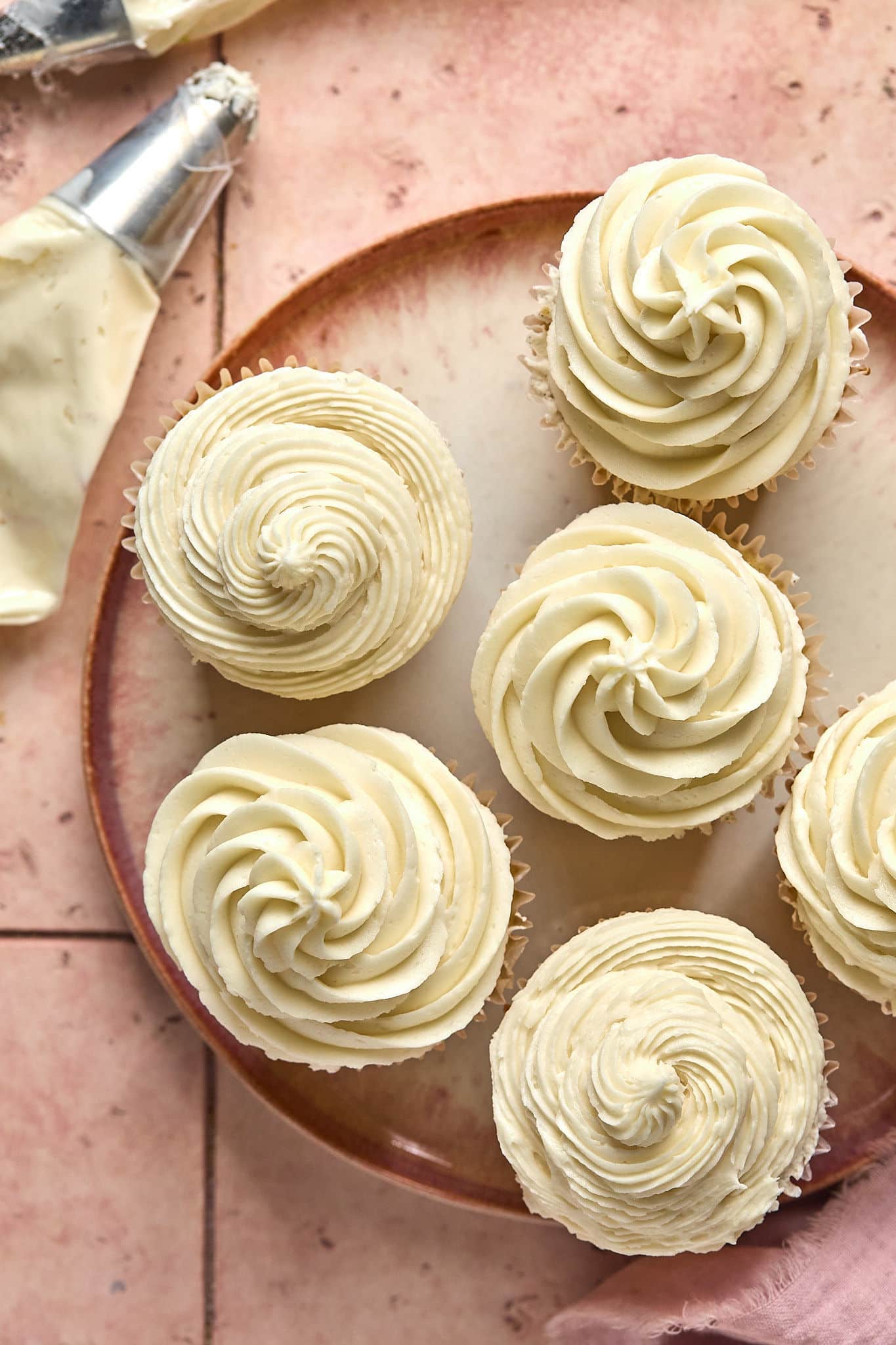 plate of cupcakes with piped, cream-colored frosting atop