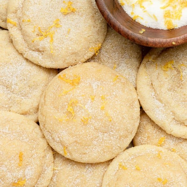 tray of sugar cookies topped with sugar and lemon zest plus a wooden bowl with sugar and lemon zest