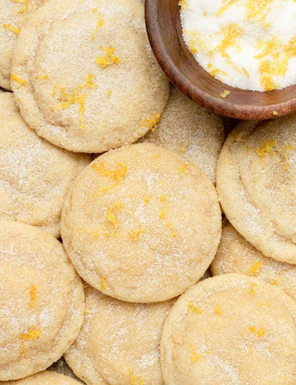 tray of sugar cookies topped with sugar and lemon zest plus a wooden bowl with sugar and lemon zest