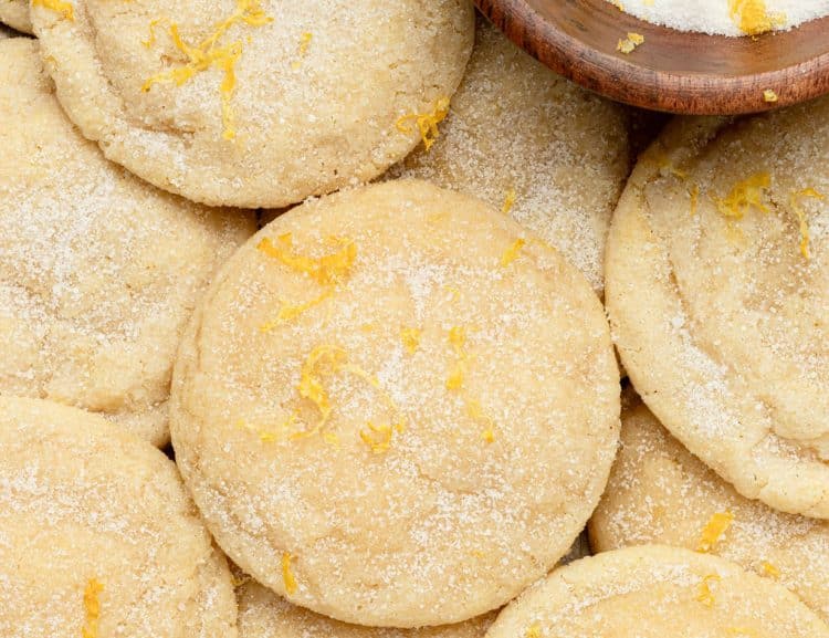 tray of sugar cookies topped with sugar and lemon zest plus a wooden bowl with sugar and lemon zest