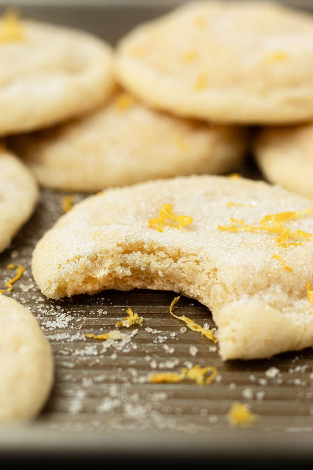 sugar cookies with lemon zest with one missing a bite in the foreground