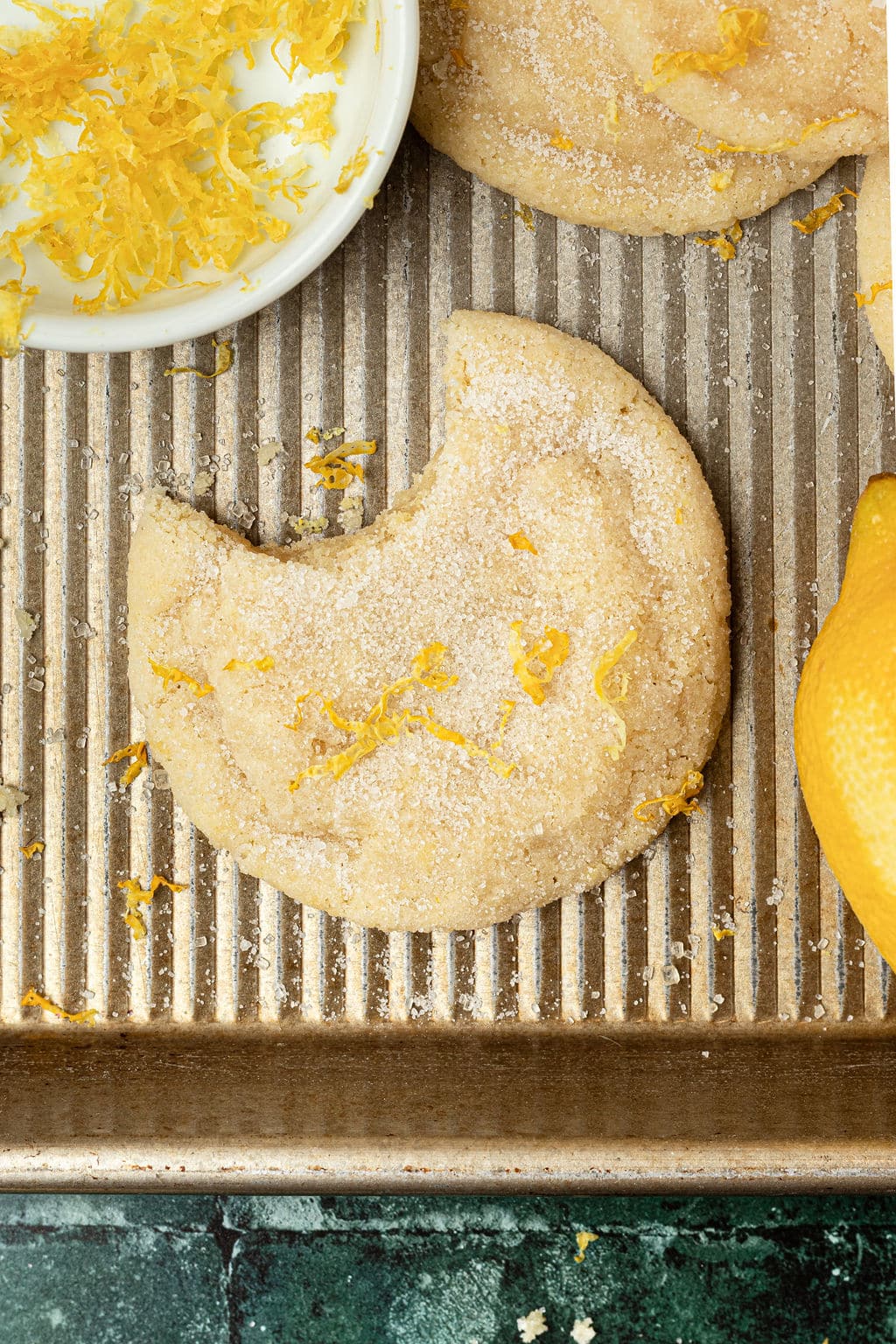 sugar cookie topped with lemon zest and sugar with a bite missing