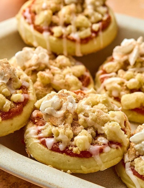 close up of plate of circle cookies with pumpkin filling, crumbles, and whipped cream topping