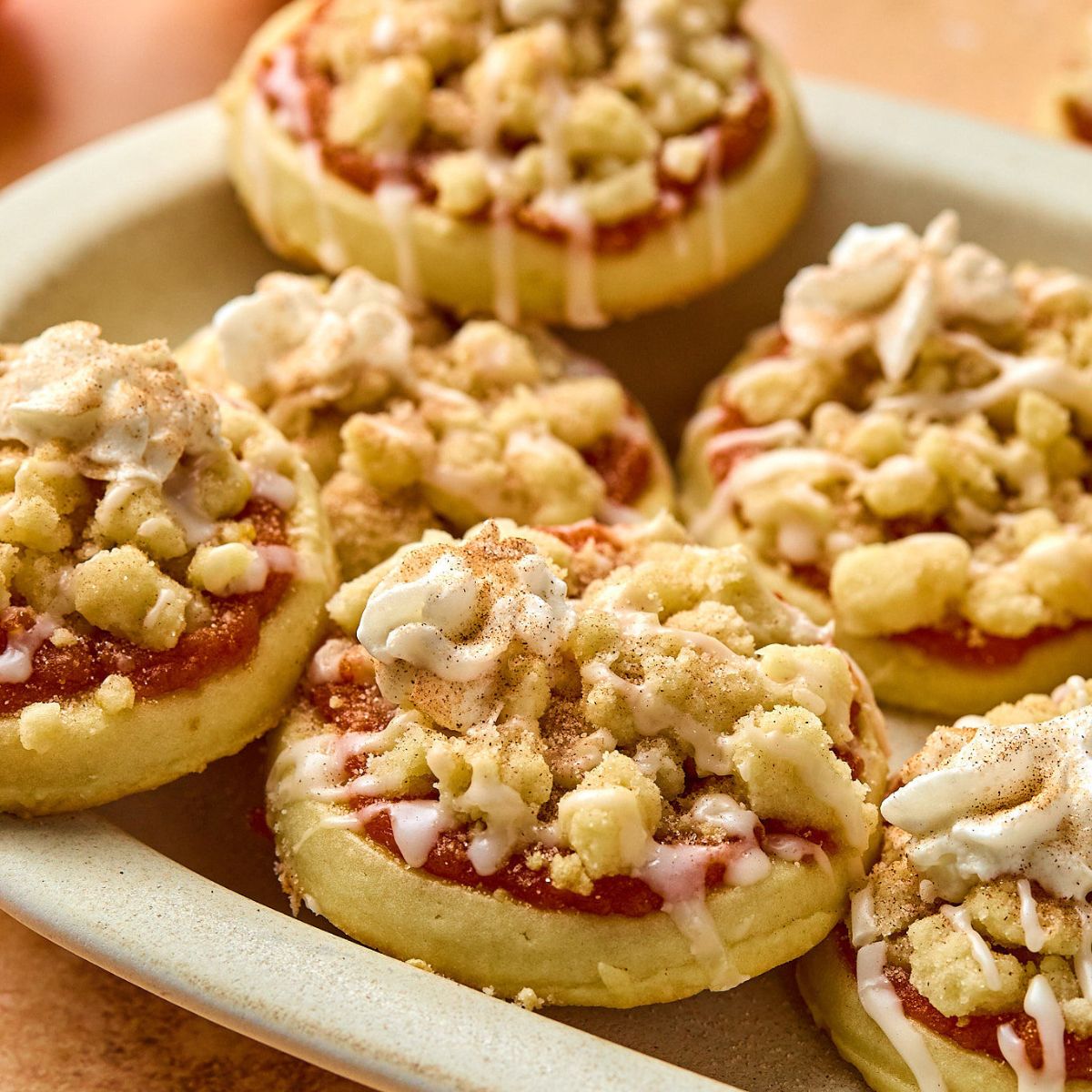 close up of plate of circle cookies with pumpkin filling, crumbles, and whipped cream topping