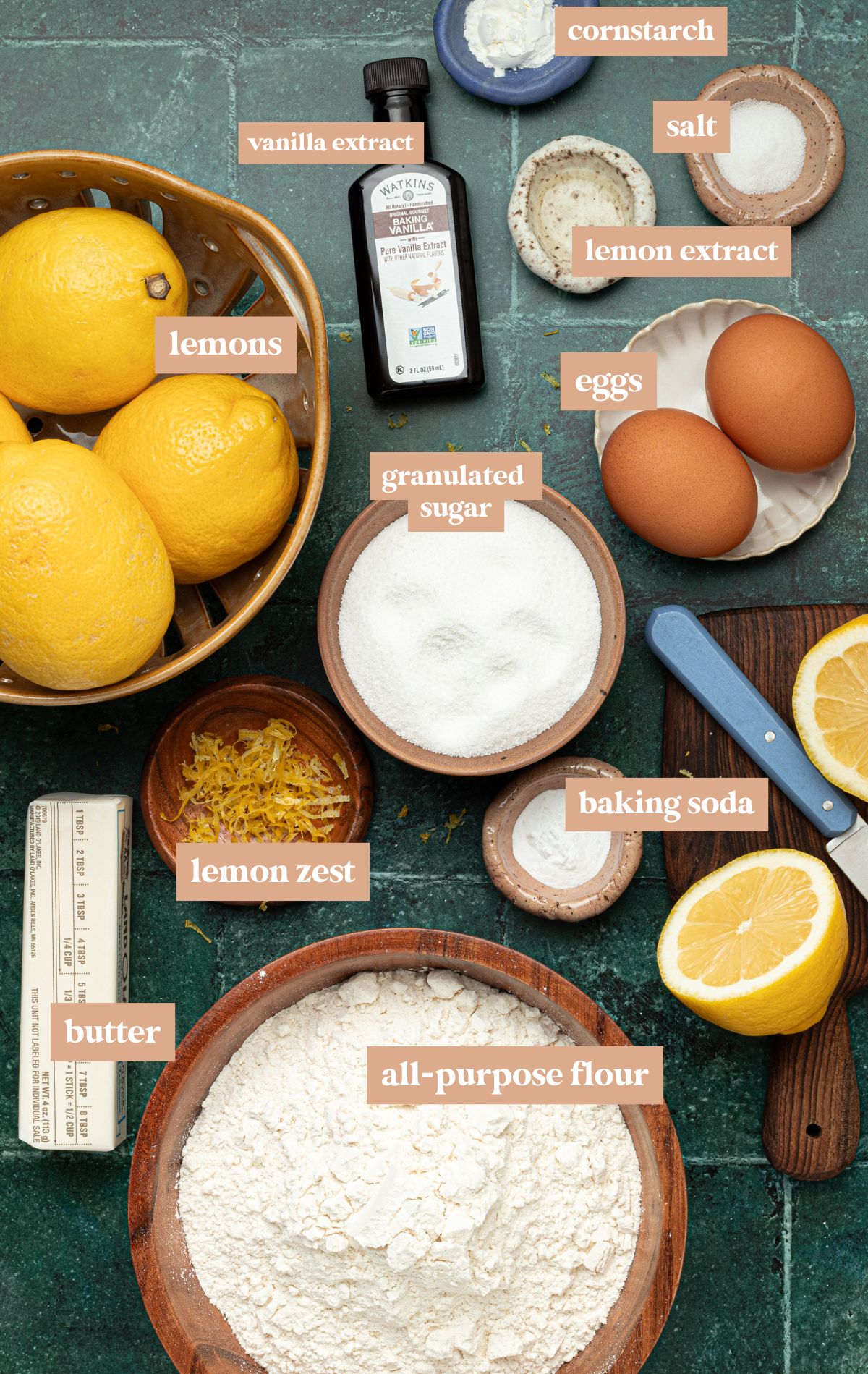 bowls with cookie ingredients including lemons, butter, flour, baking soda, lemon zest, sugar, eggs, vanilla extract, lemon extract, salt, and cornstarch