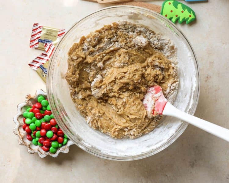 clear mixing bowl, cookie dough mixed together, spatula resting in bowl