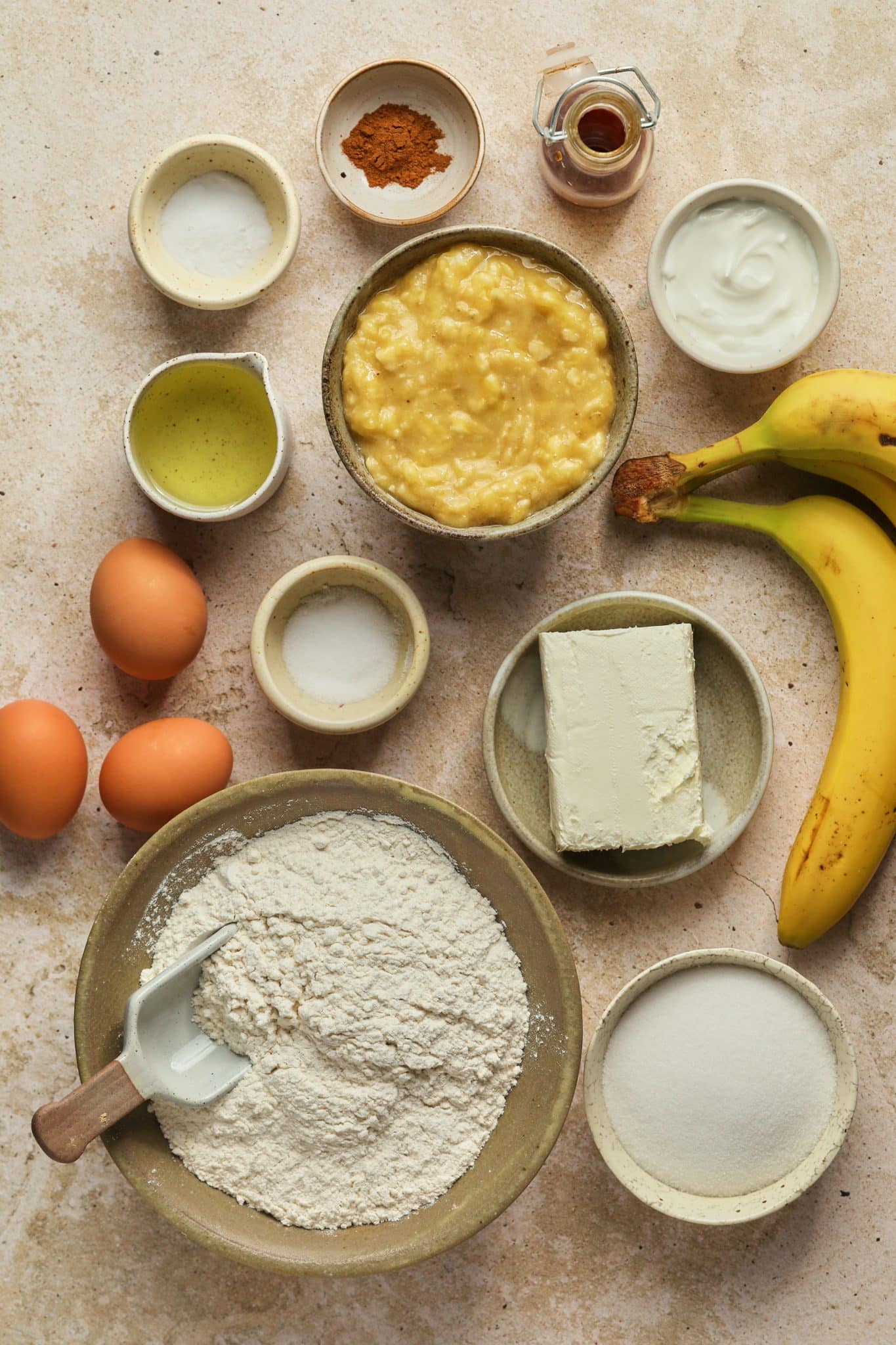 ingredients to make banana bread with cheesecake in the middle divided into small bowls. 