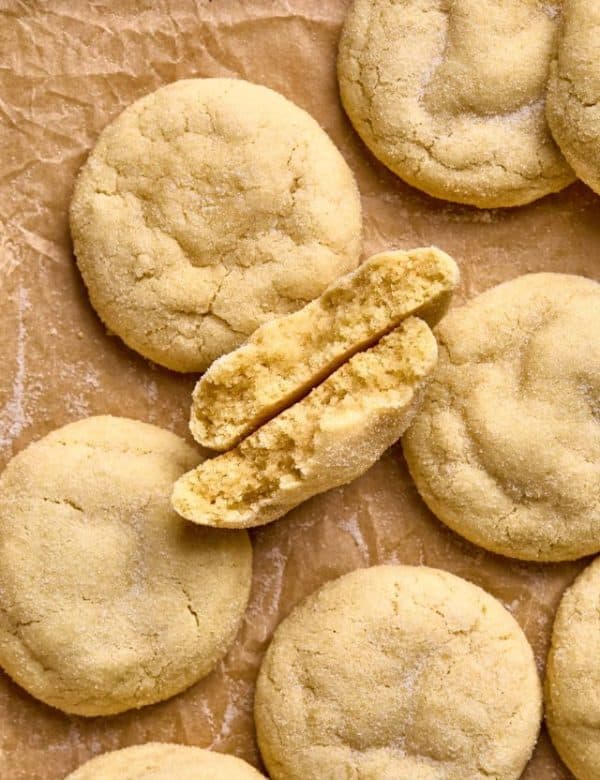 sugar cookies on parchment paper with one cookie broken in half with broken halves facing up