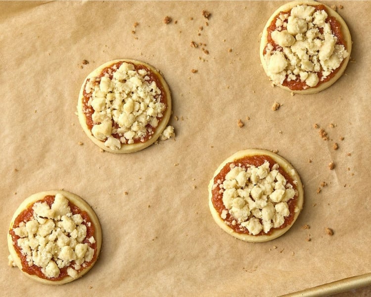 four sugar cookies with pumpkin and crumble topping, lightly browned out of the oven