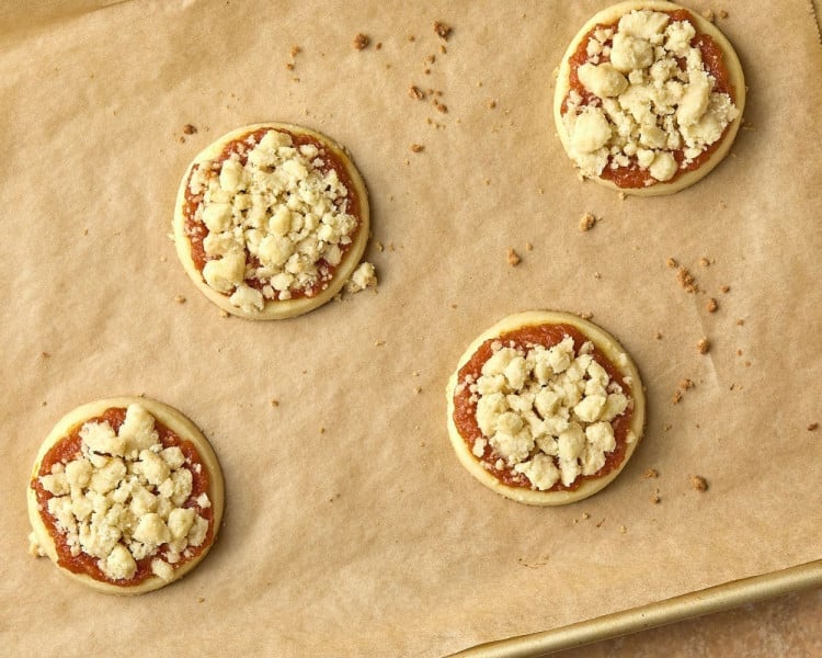 cookies with pumpkin spread and crumbles on top, on parchment paper