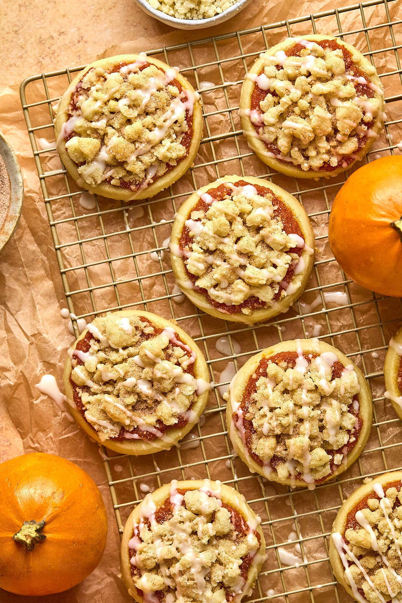 gold cooling rack with circle sugar cookies topped with pumpkin, streusel and glaze