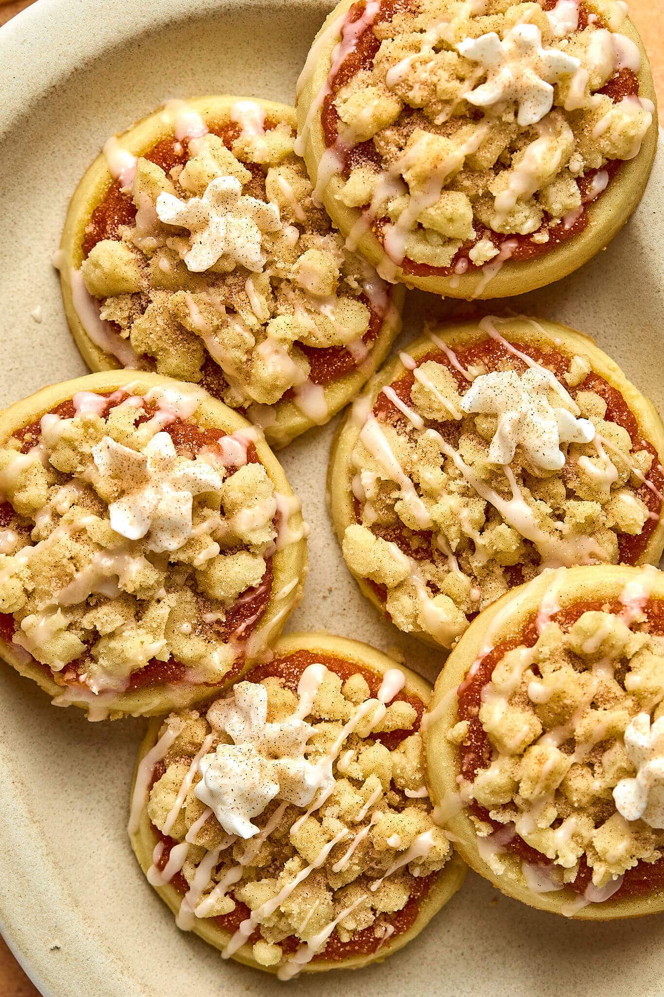 circular sugar cookies with pumpkin, streusel, drizzle of glaze and dollop of whipped cream