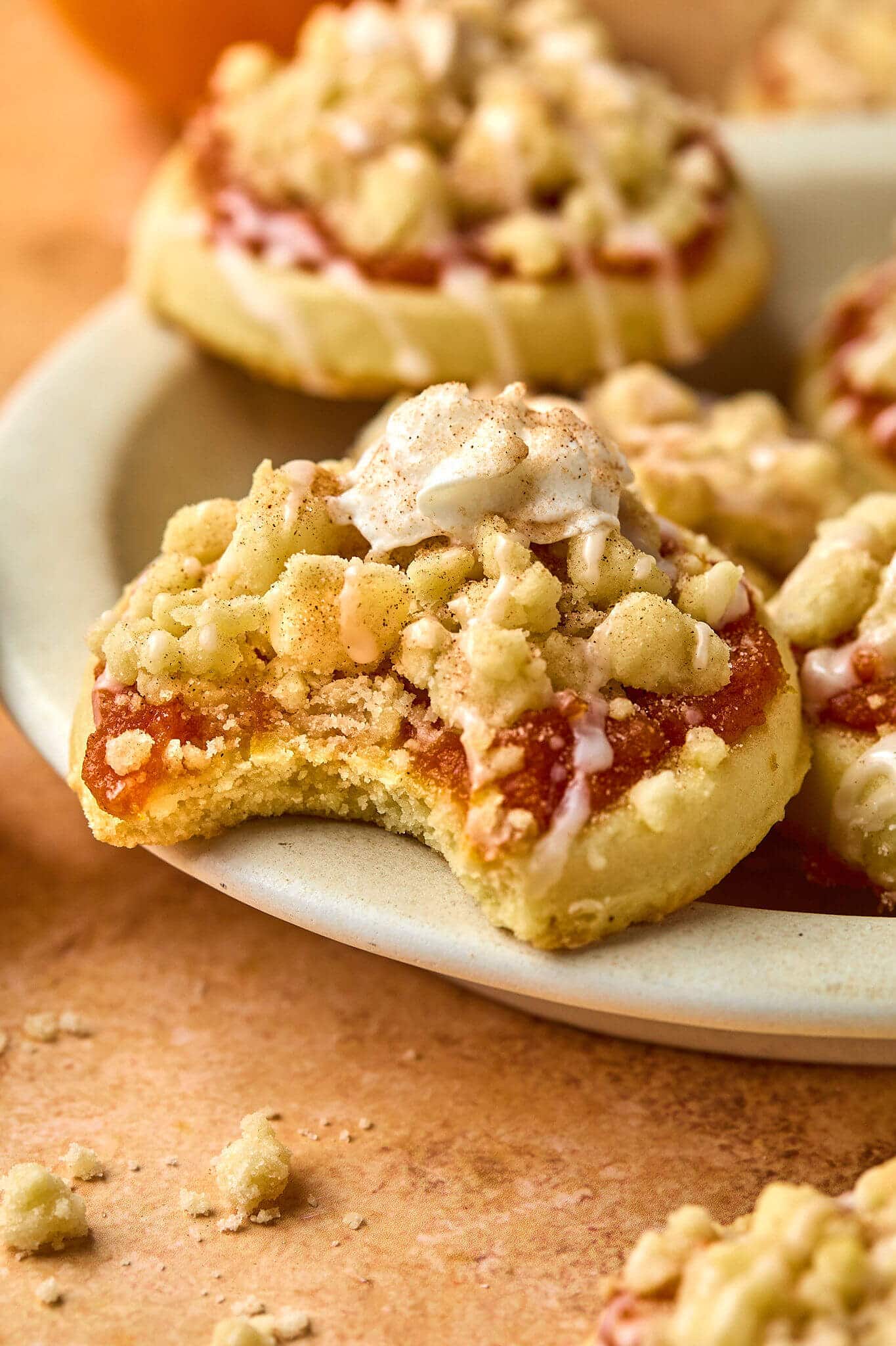 close up of cookie with pumpkin, crumbles, and whipped cream toppings with a bite taken out