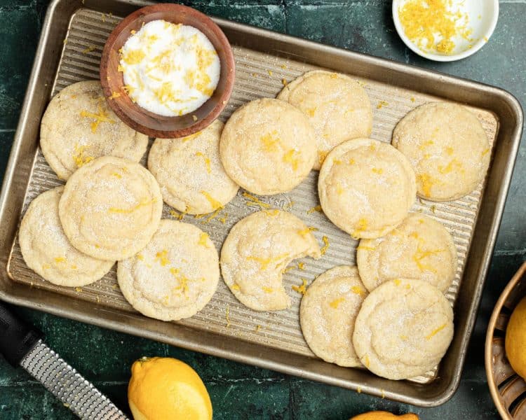 gold cookie sheet full of cookies topped with sugar and lemon zest