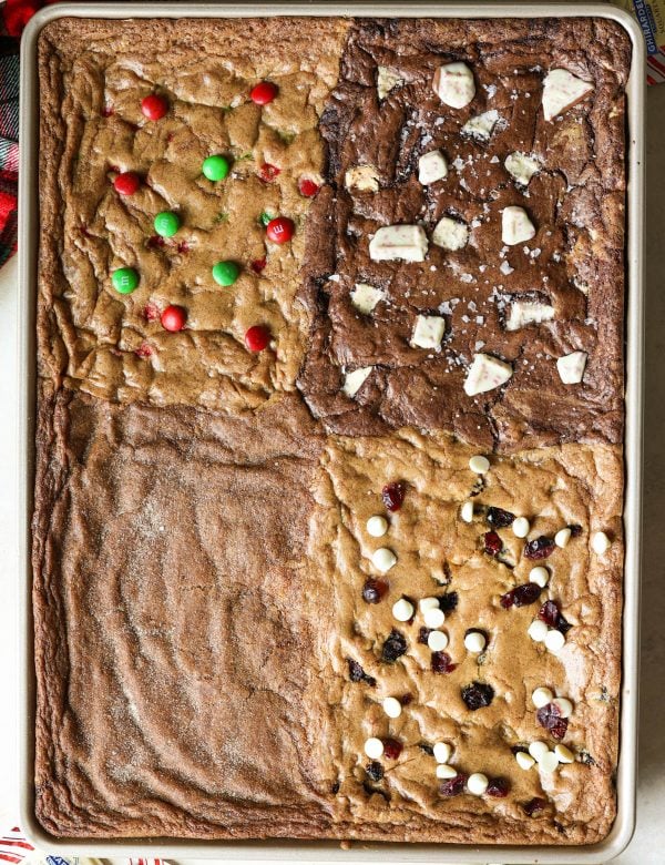 gold sheet pan with four types of cookies - m&m, chocolate peppermint, gingerbread, and cranberry white chocolate chip