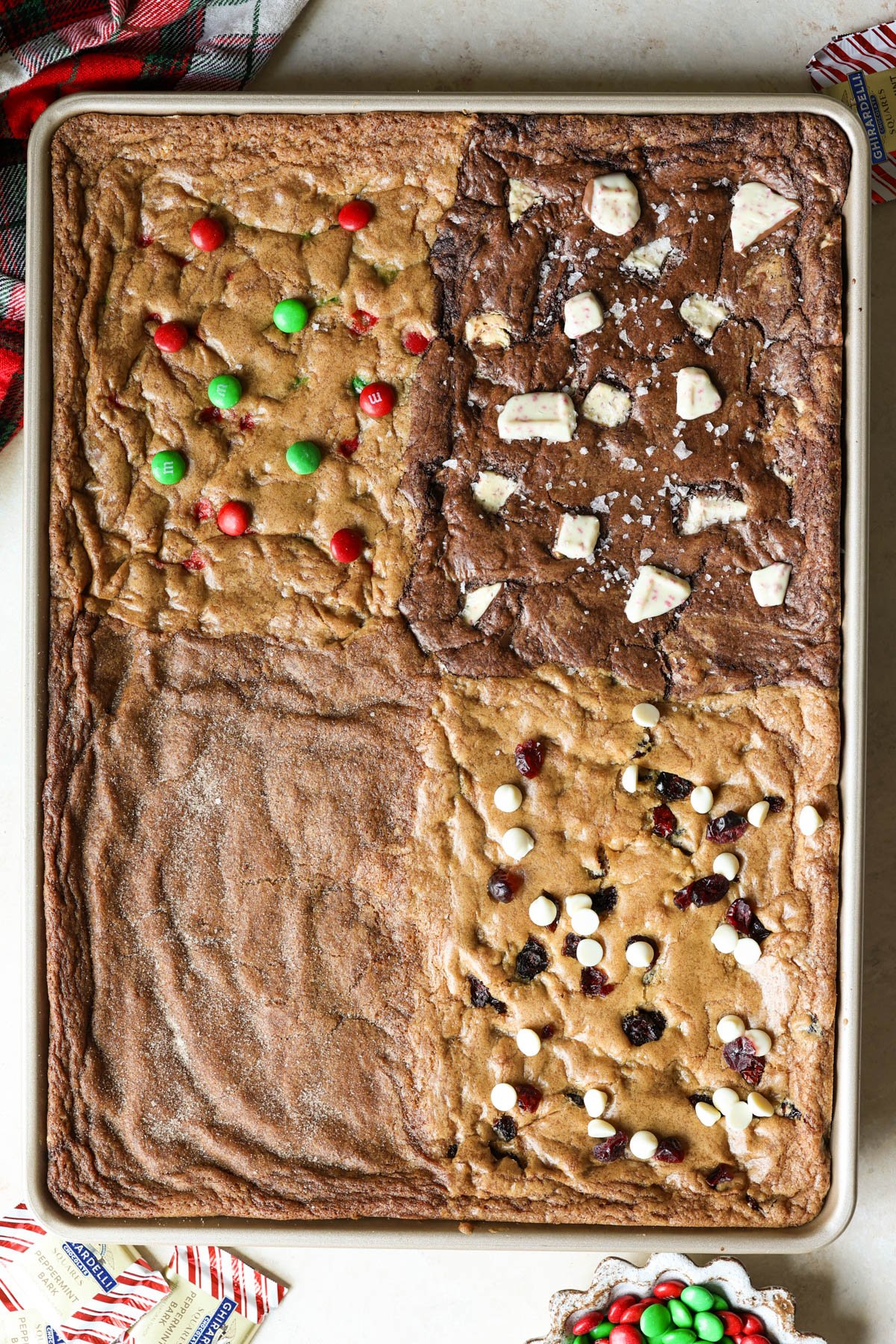 gold sheet pan with four types of cookies - m&m, chocolate peppermint, gingerbread, and cranberry white chocolate chip