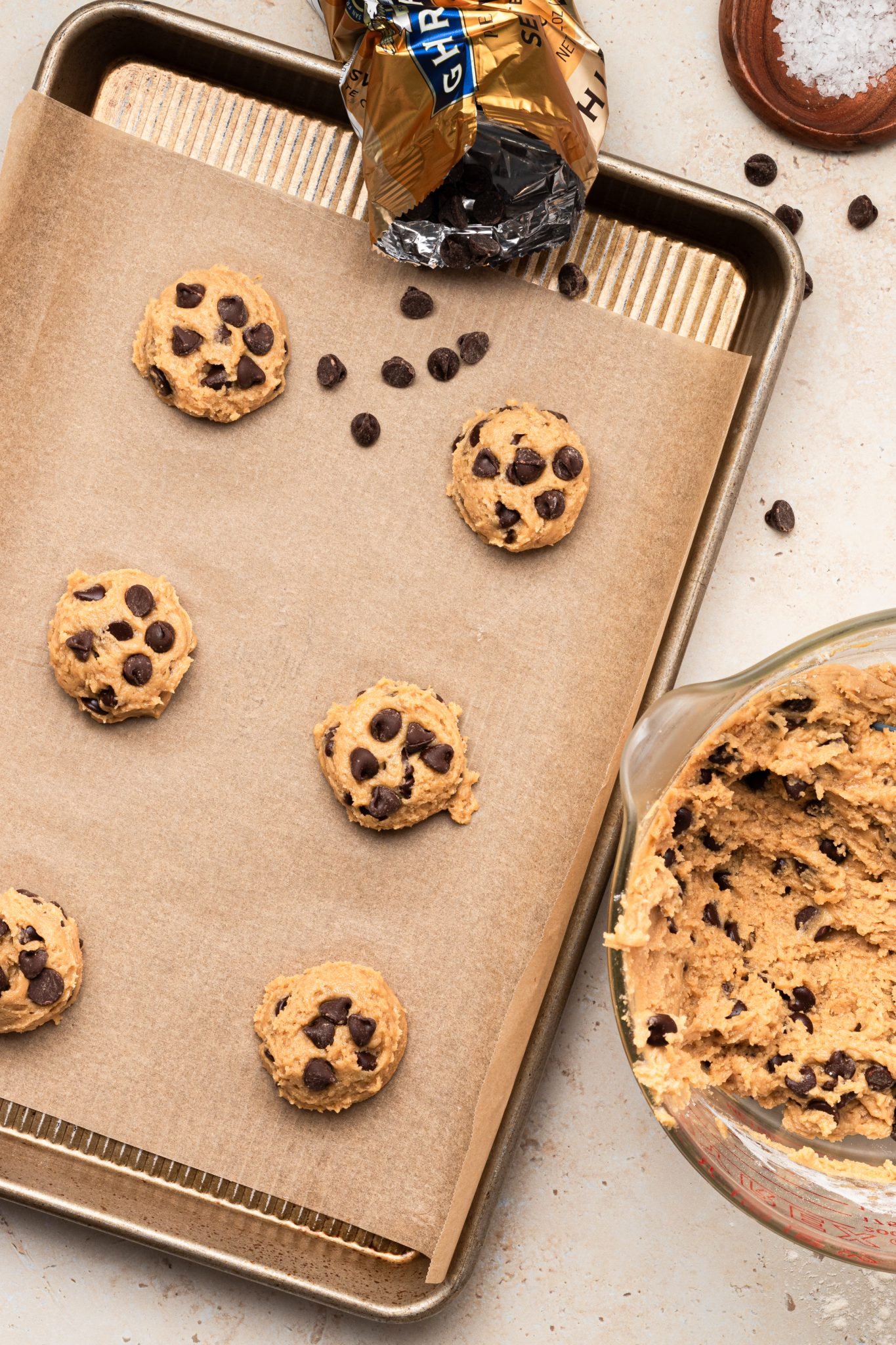 scooped cookie dough on a cookie sheet with chocolate chips on top.