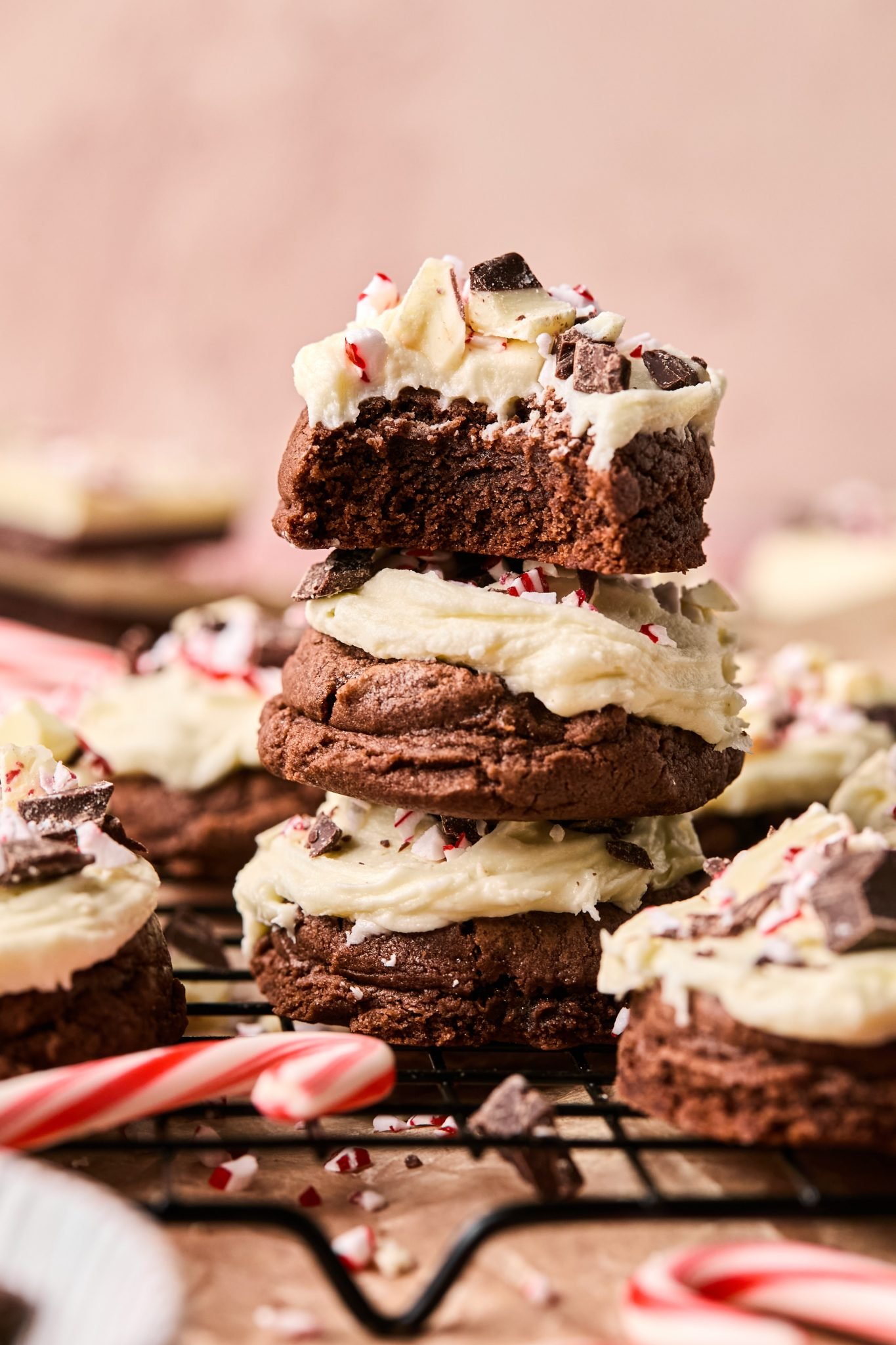 a stack of peppermint cookies with white buttercream frosting on top and garnished with peppermint. 