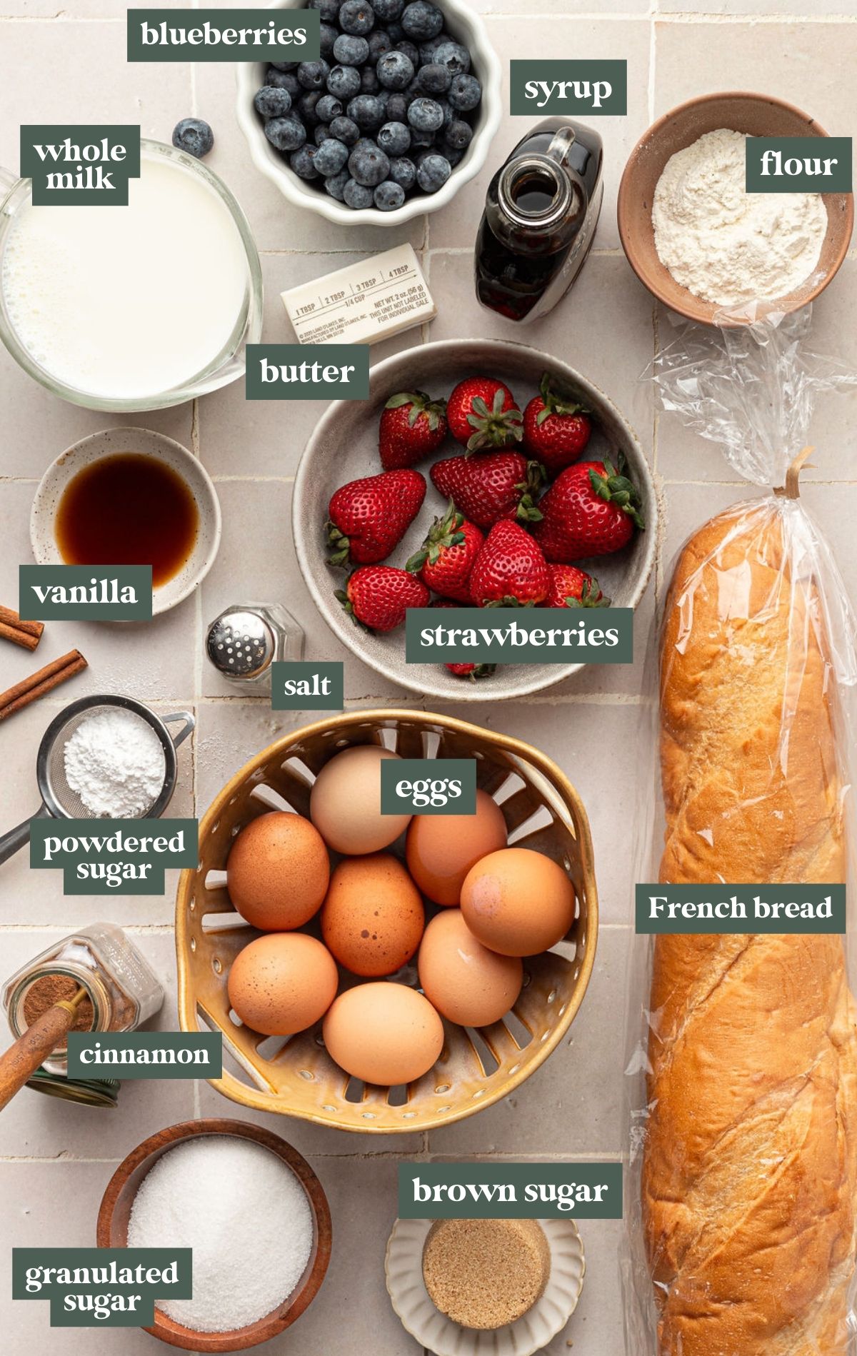 Bowls of ingredients including milk, blueberries, syrup, flour, butter, vanilla, strawberries, salt, powdered sugar, eggs, French bread, cinnamon, granulated sugar, and brown sugar.