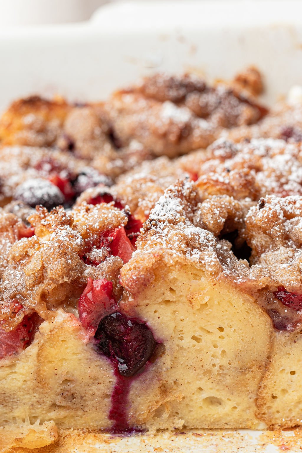 Close up image of slice of French toast with berries topped with cinnamon sugar.