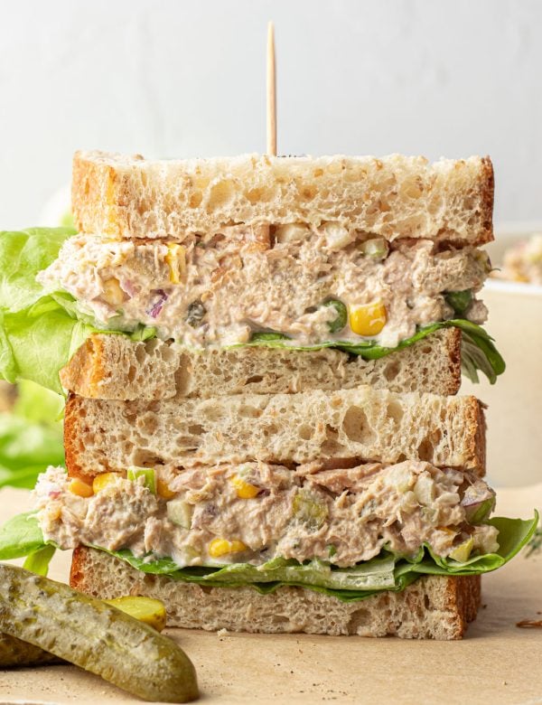 Two halves of a sandwich stacked on another, filled with tuna salad and lettuce.