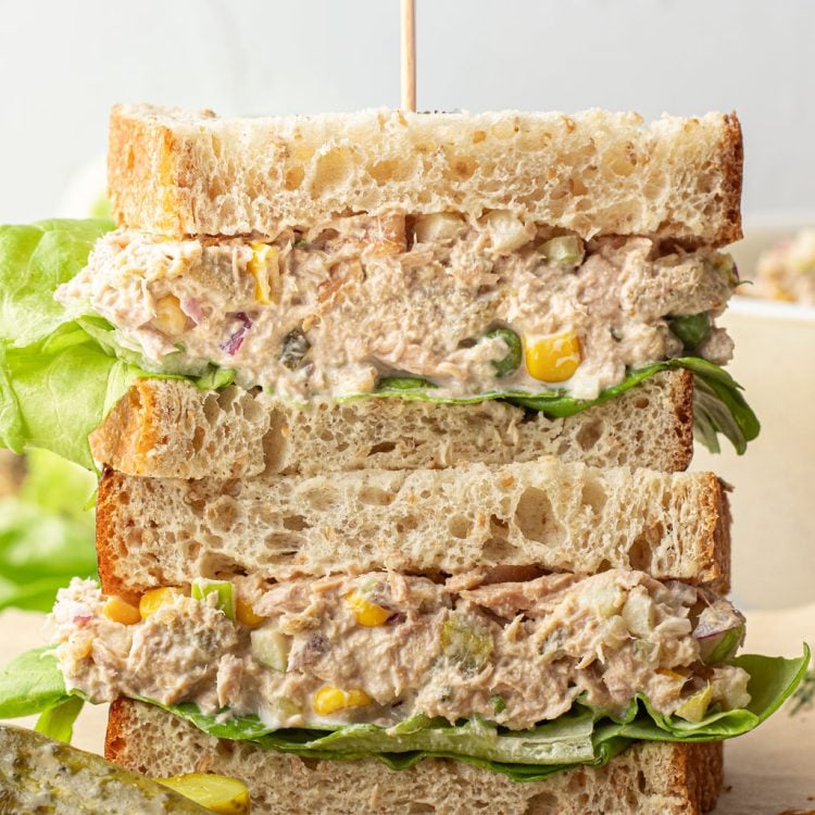 Two halves of a sandwich stacked on another, filled with tuna salad and lettuce.