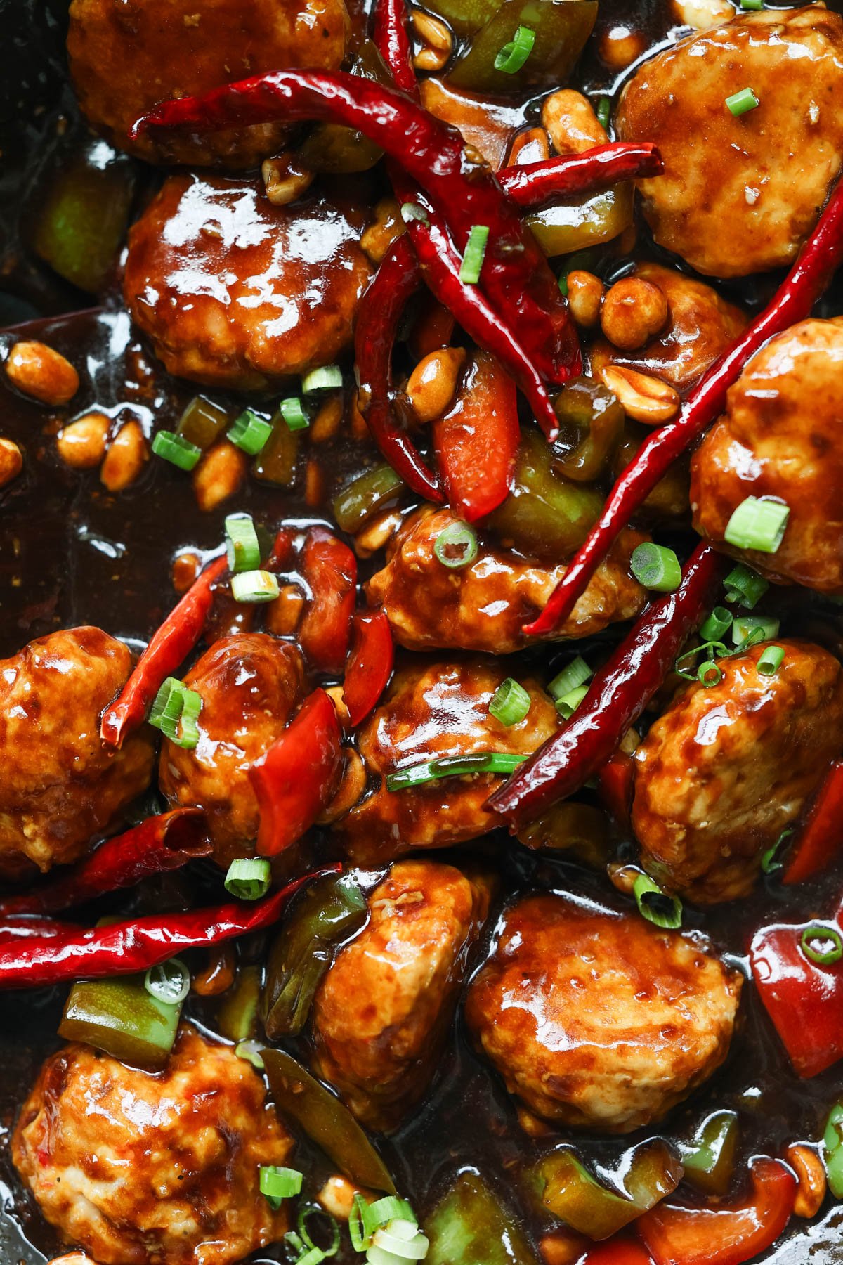 a close up image of kung pao chicken meatballs with arbol chiles. 